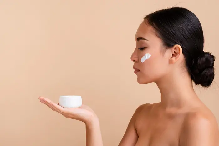 Femme appliquant la crème Atomy Absolute sur sa joue